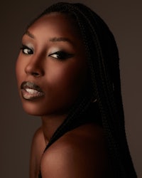 a black woman with braided hair posing on a dark background